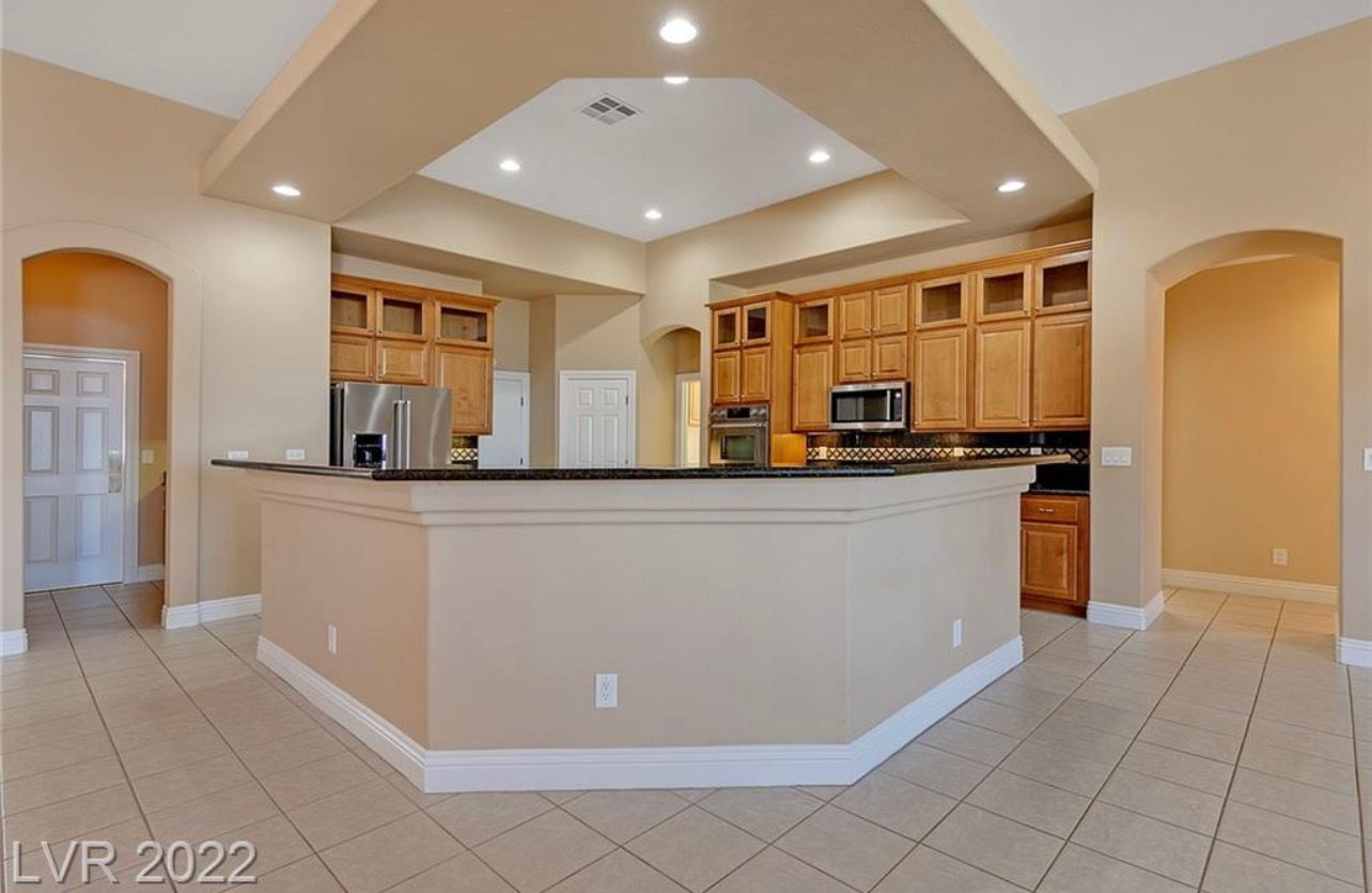 Kitchen with beige cabinets, black countertop, and tile floor.