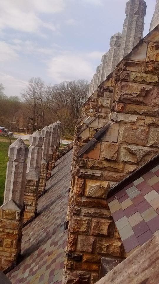 A stone wall with a roof and trees in the background.