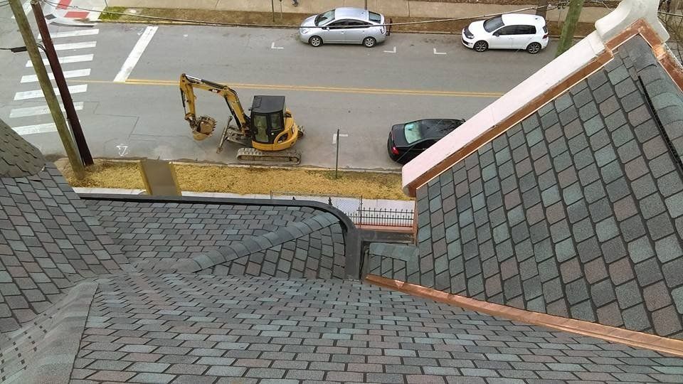 A yellow excavator is parked on the side of the road next to a roof.