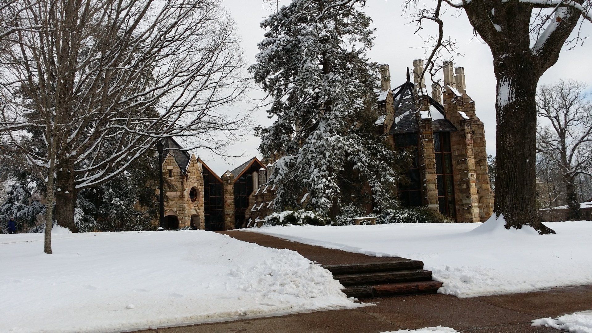 A snowy park with a stone building in the background