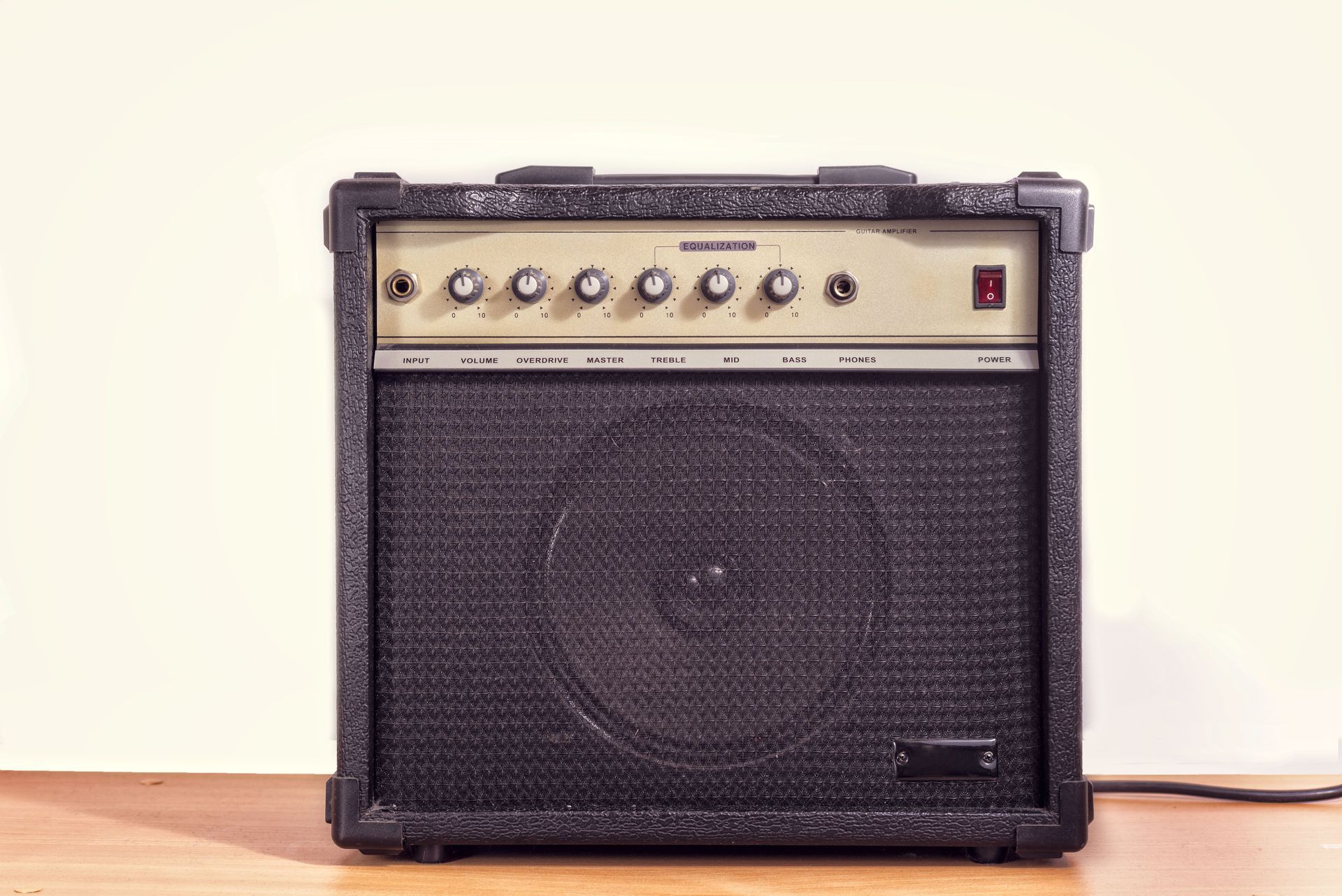 Black and beige guitar amplifier on a wooden surface, against a white wall.