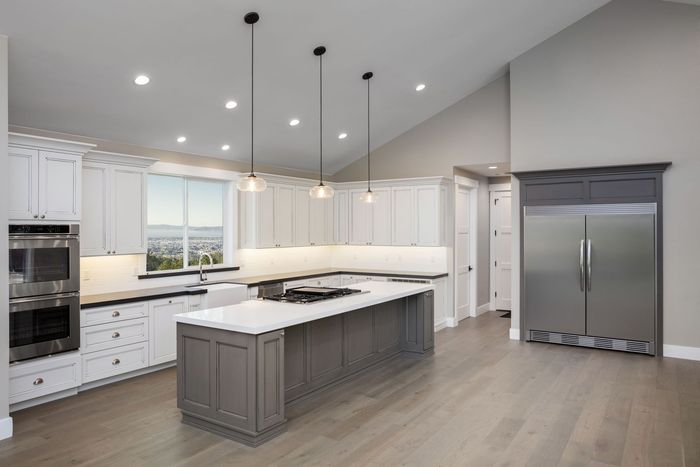 A kitchen with white cabinets , stainless steel appliances , and a large island.
