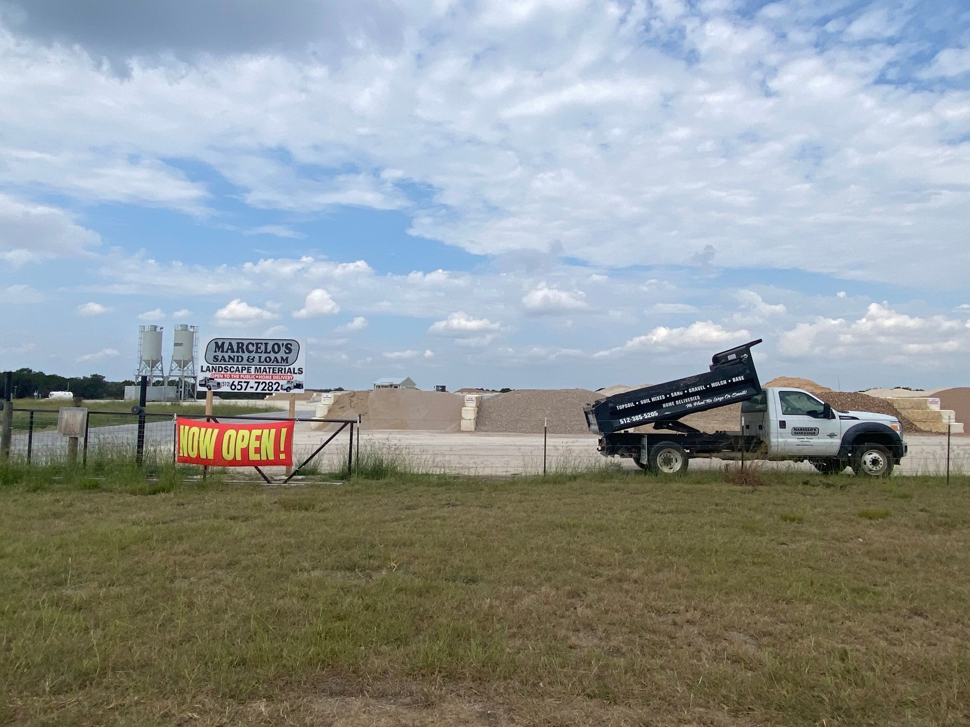 A dump truck is parked in a grassy field next to a sign