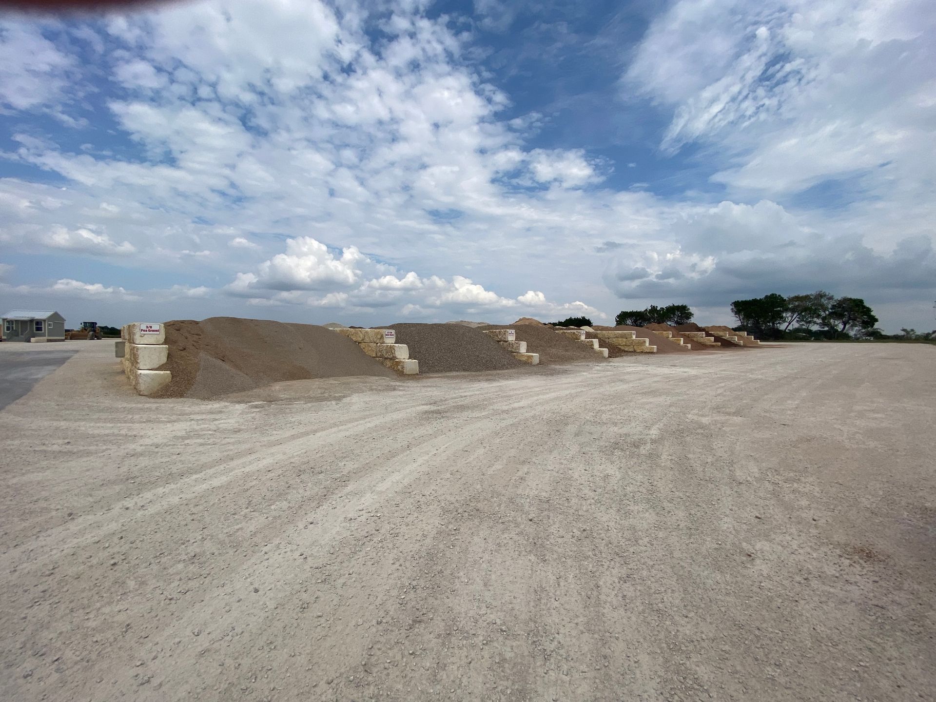A dirt road with a blue sky and clouds in the background