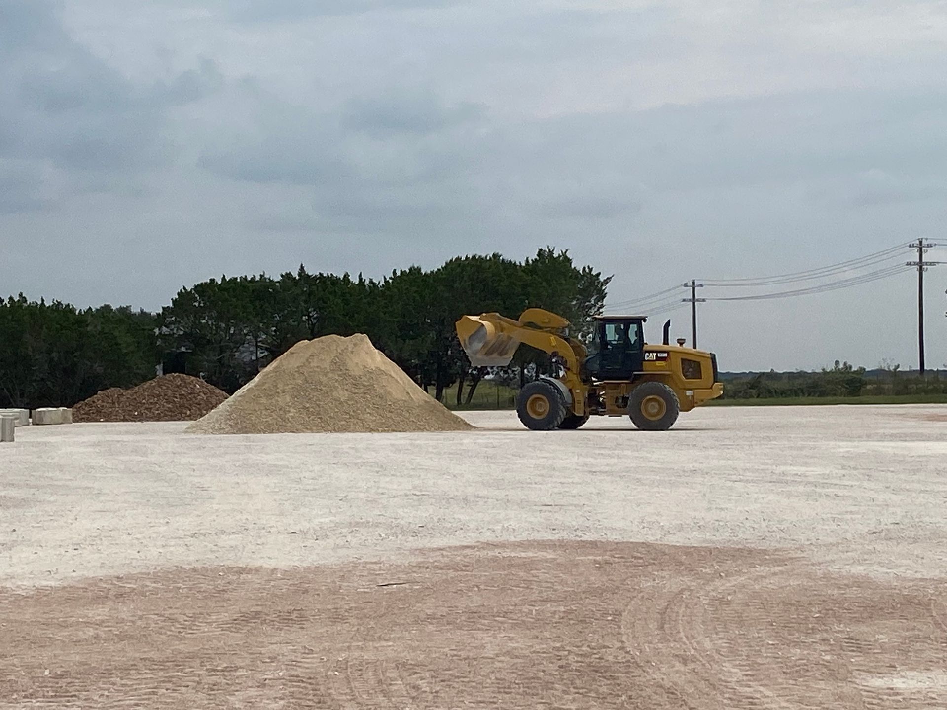 A bulldozer is moving a pile of dirt in a field
