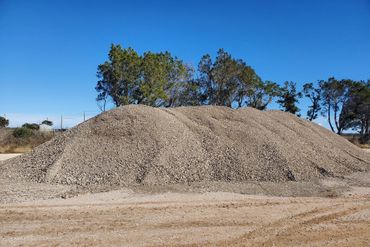 a large pile of gravel is sitting in the middle of a dirt field .