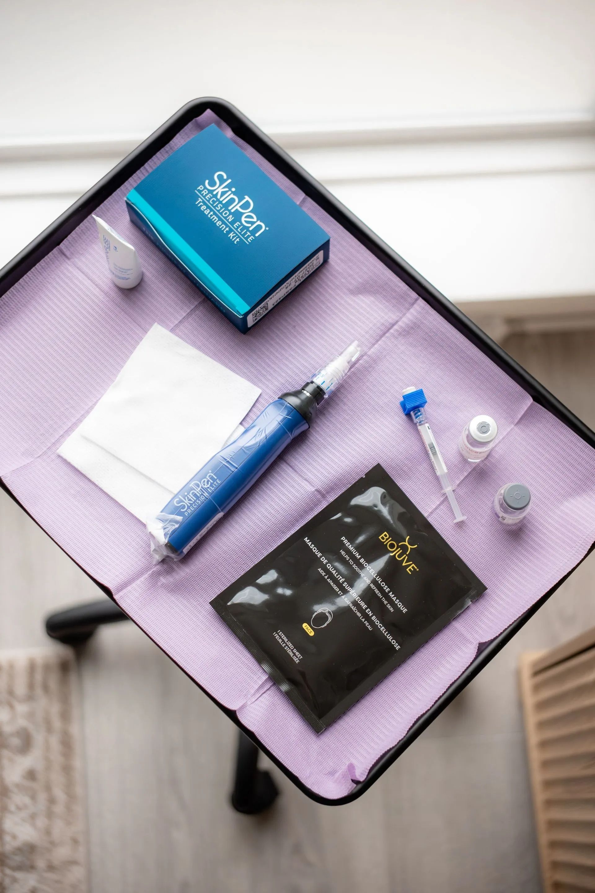 Blue medical syringe and supplies on a purple tray table near a window.