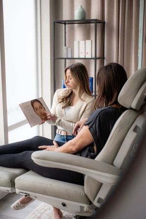 Two people sit in reclining chairs, looking at a book in a cozy living room.