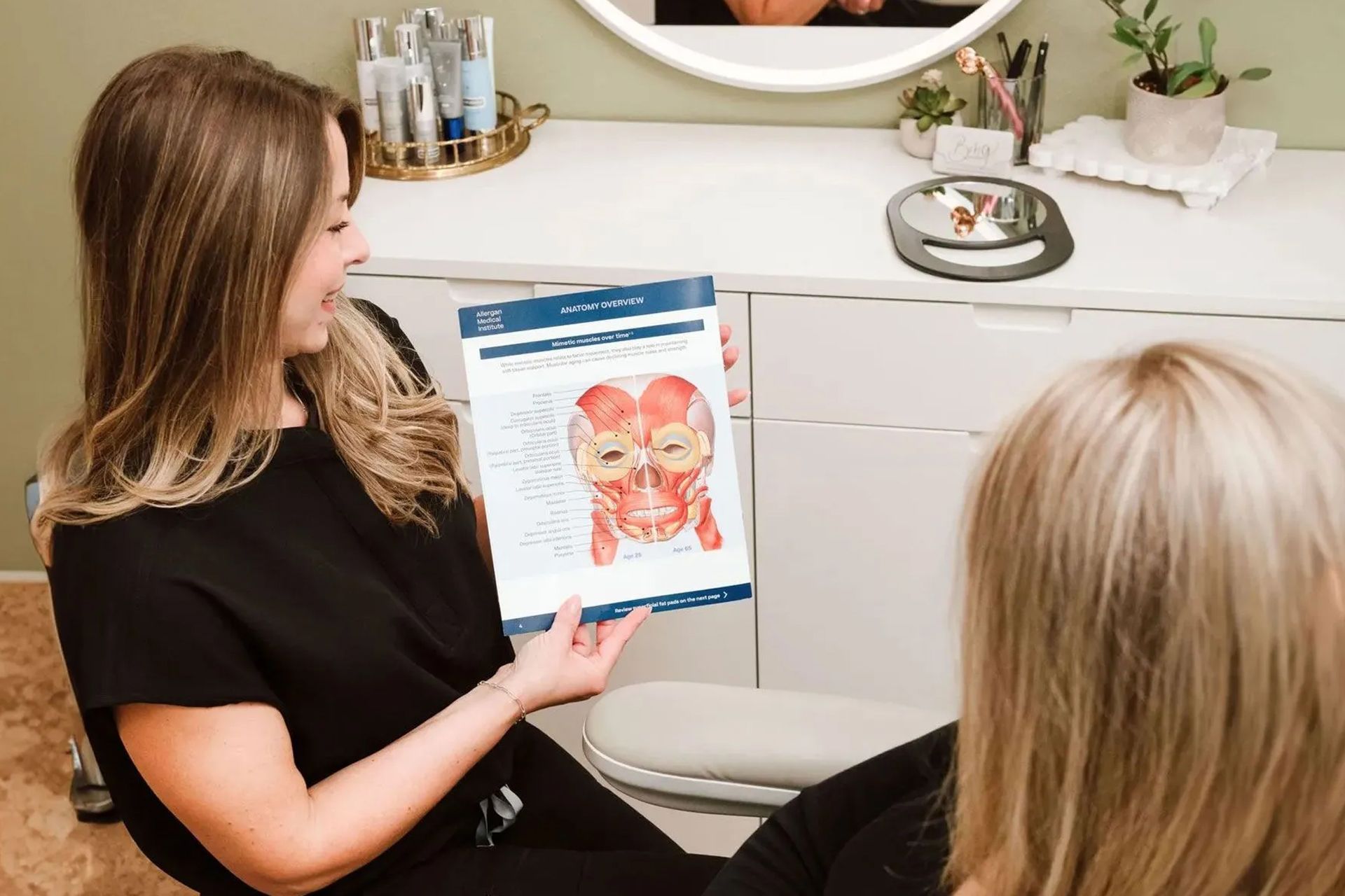 Woman in black showing a dental diagram during a consultation in a bright office