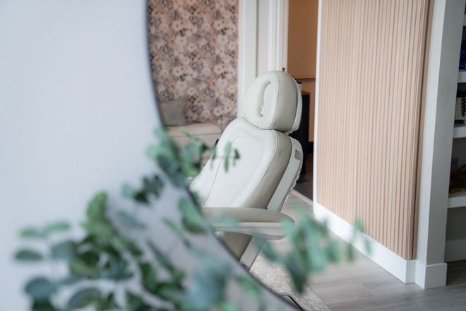 White massage chair in a quiet room beside a wood-paneled wall and floral partition