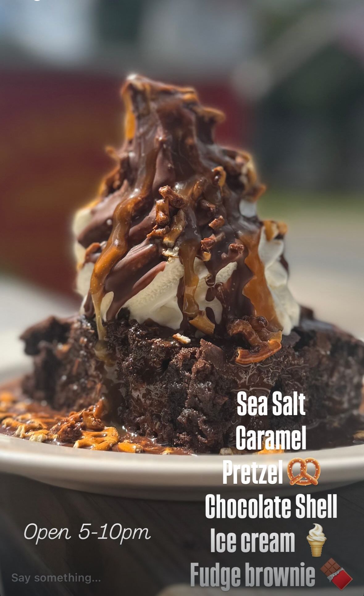 Sea salt caramel pretzel chocolate ice cream sundae with handwritten flavors and open hours sign.