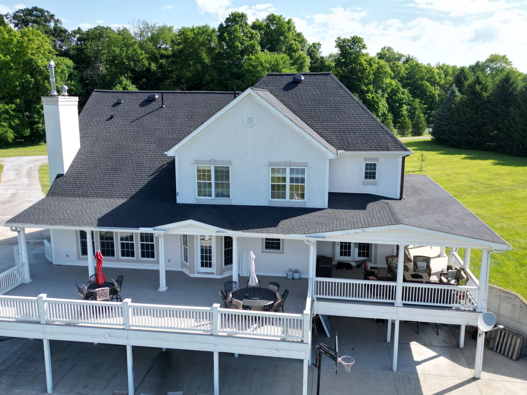 An aerial view of a large white house with a large deck.