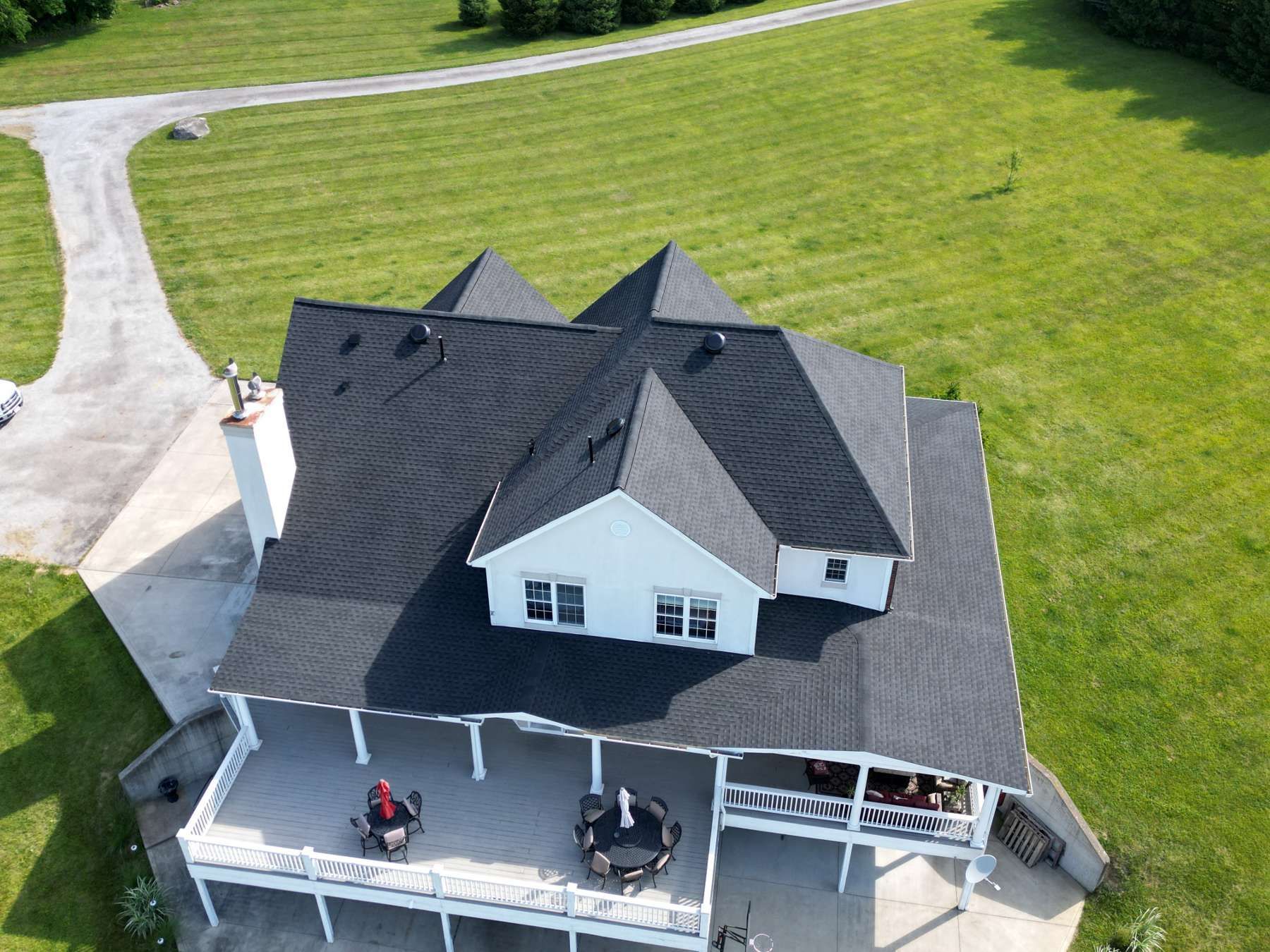 An aerial view of a large white house with a black roof
