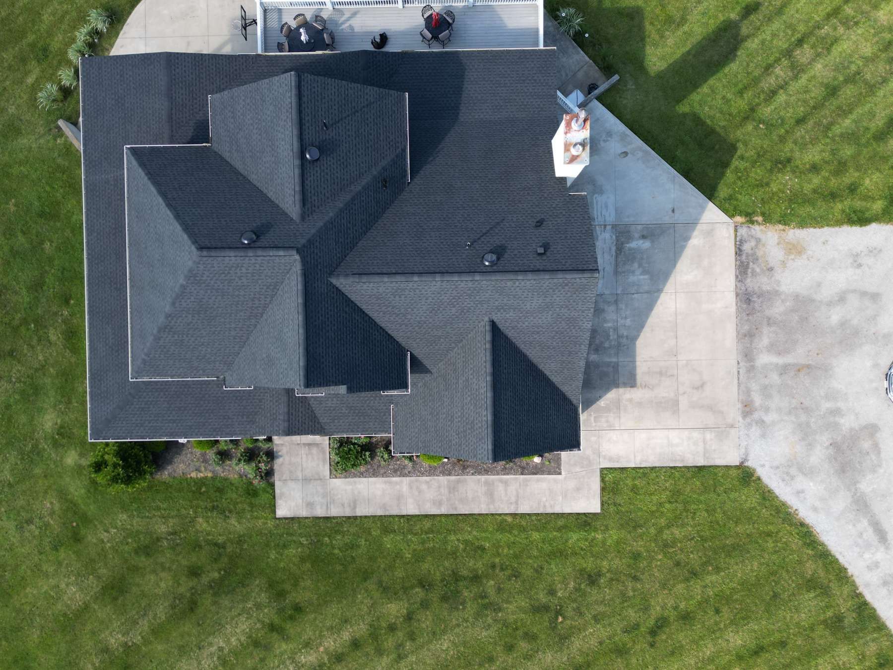 An aerial view of a house with a black roof and a driveway.