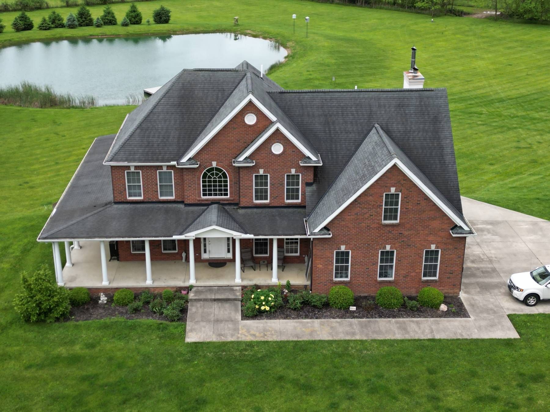An aerial view of a large brick house with a white truck parked in front of it.