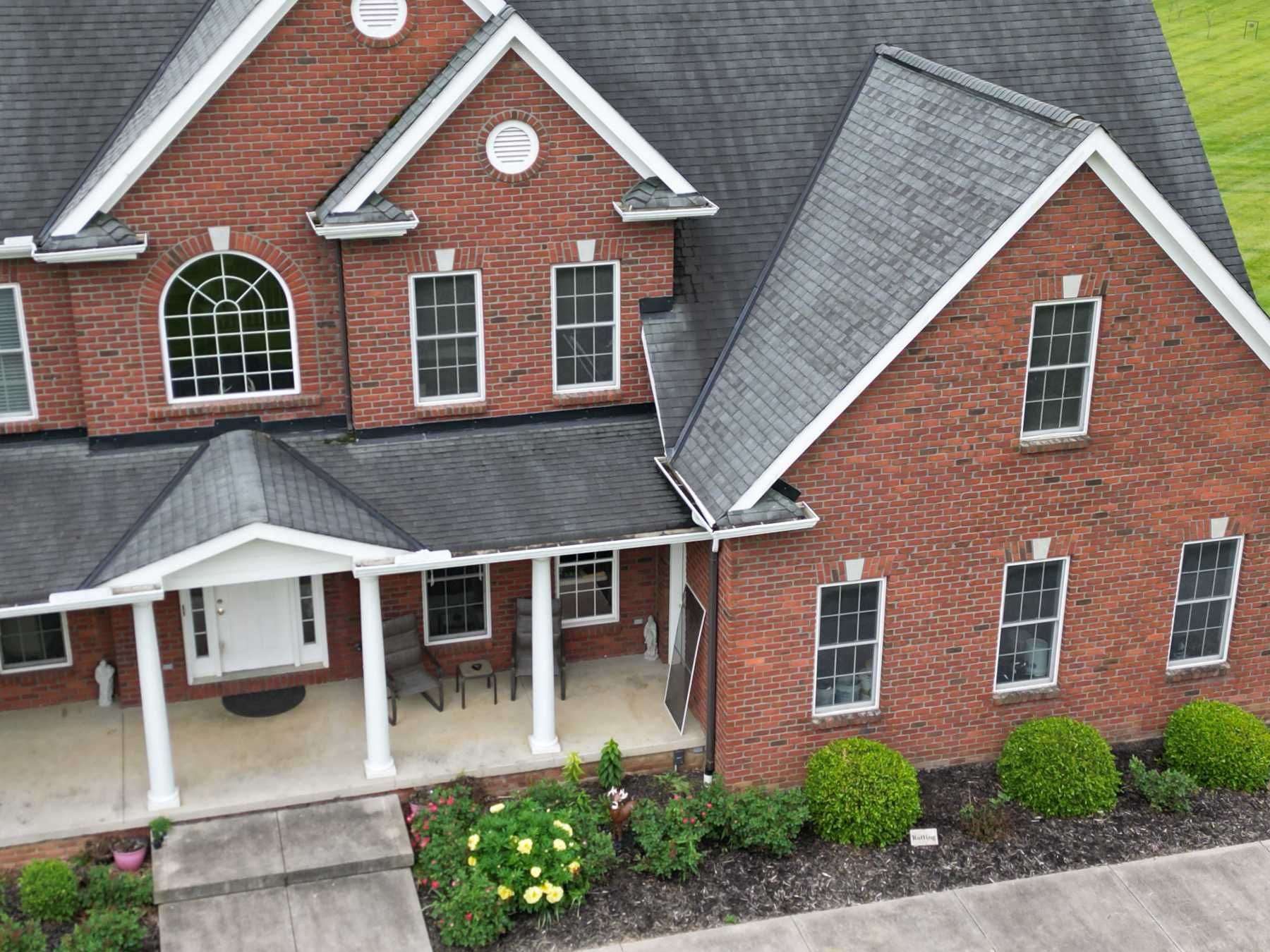 An aerial view of a large brick house with a black roof