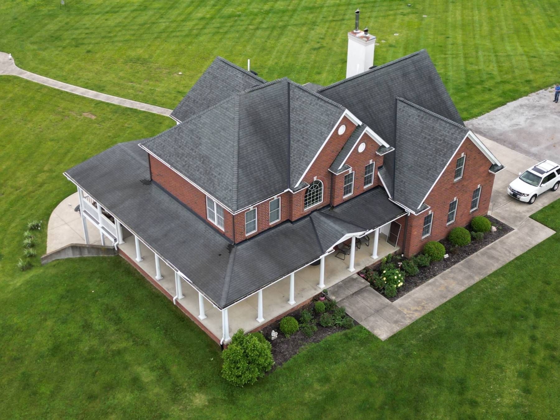 An aerial view of a large brick house with a car parked in front of it.
