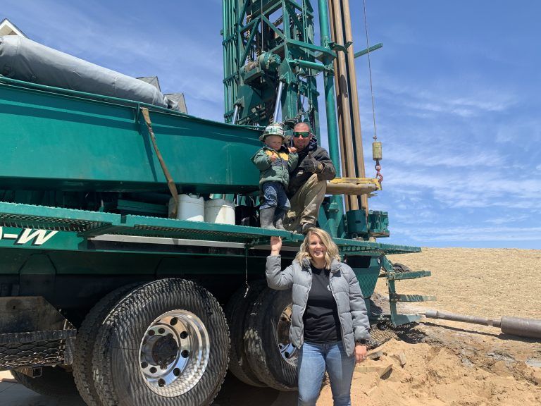 family standing by well drilli