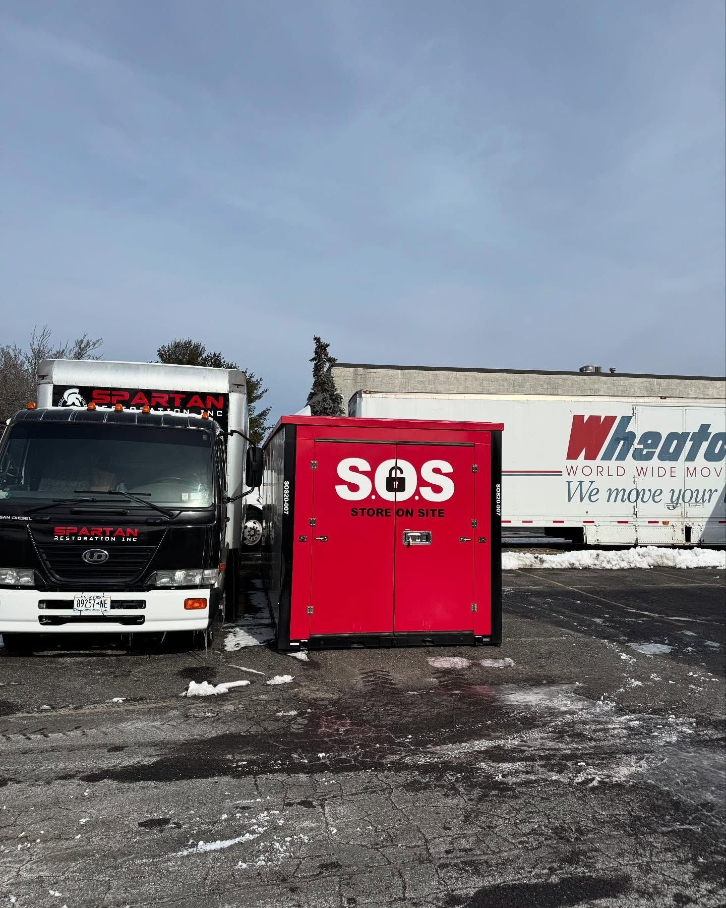 Red SOS storage container with truck and Whakatō truck in a snowy parking lot.