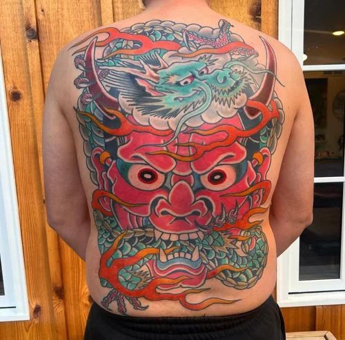 Back view of a man with a colorful full-back dragon tattoo in red, teal, and blue