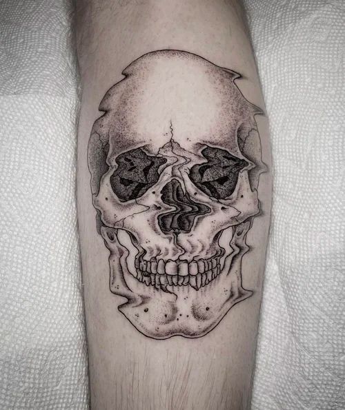 Black-and-gray skull tattoo on a forearm, centered on pale skin.