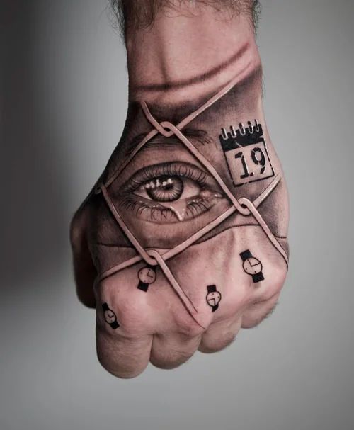 Tattooed hand with eye and calendar designs, wrapped in crisscrossing bands against a gray background