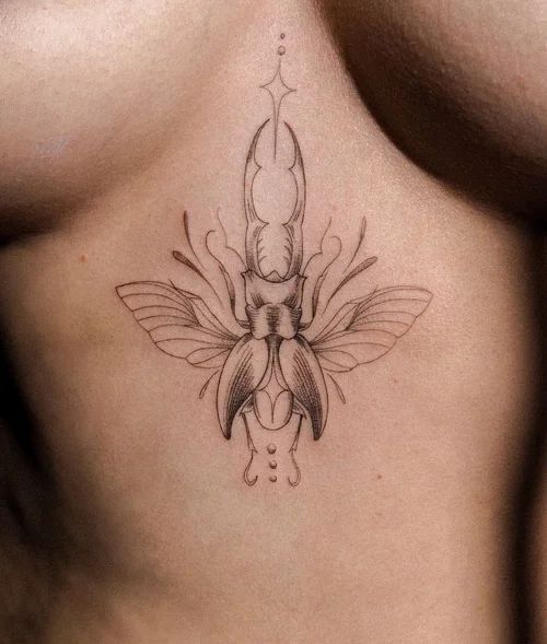 Delicate black line-art beetle tattoo centered on a person’s chest skin.