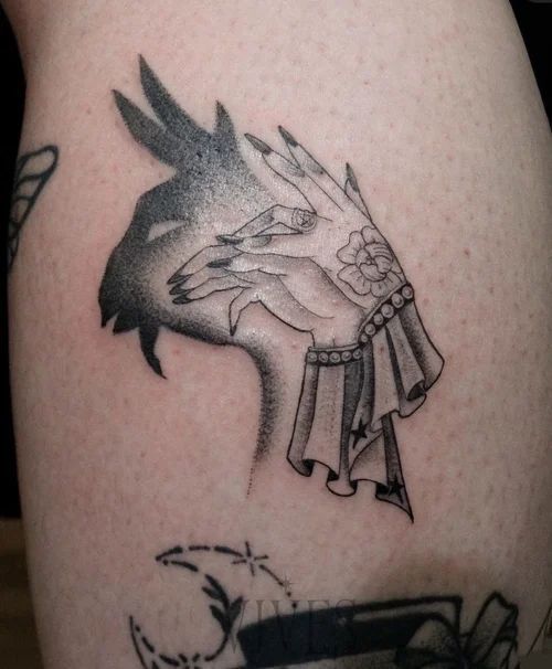 Black-and-gray tattoo of hands covering a face, with a bird-like head and arm drapery on skin
