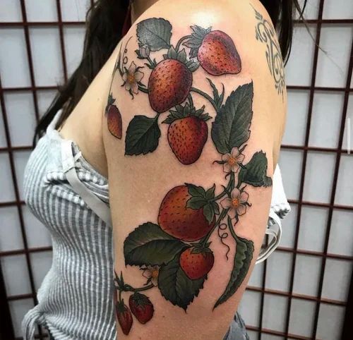 Upper arm tattoo of strawberries and leaves on a person’s arm