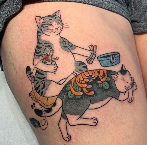 Colorful cat tattoo with two cats, one standing and one sleeping, decorated with floral and abstract details