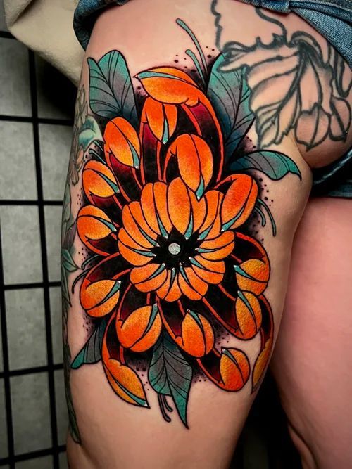 Close-up of a thigh tattoo featuring an orange flower with green leaves and a black center