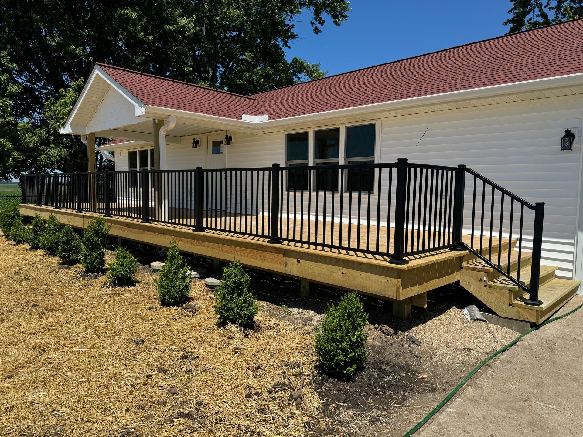A white house with a large deck, railings, and stairs