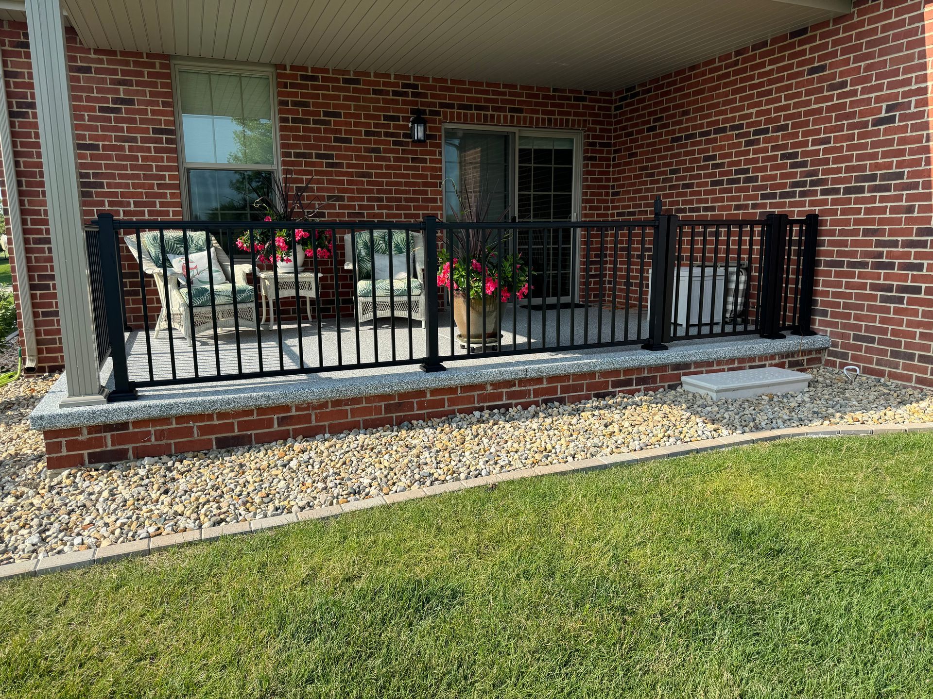 A brick house with a porch with a black railing.
