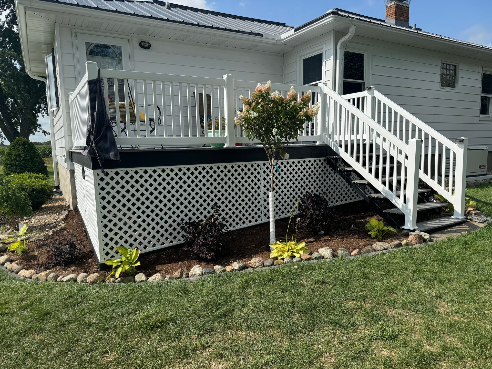 A white house with a white deck, railings, and stairs.