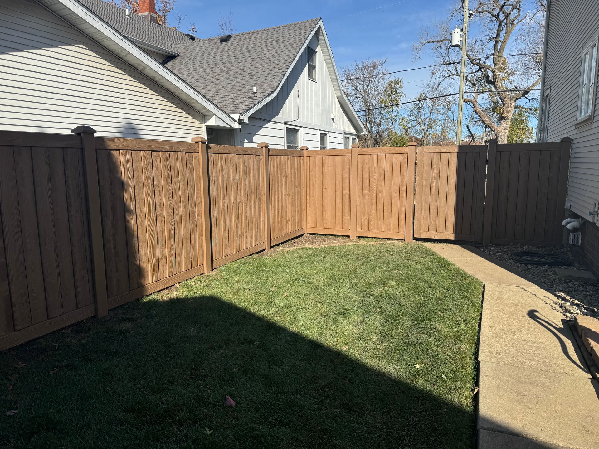 There is a wooden fence in the backyard of a house.