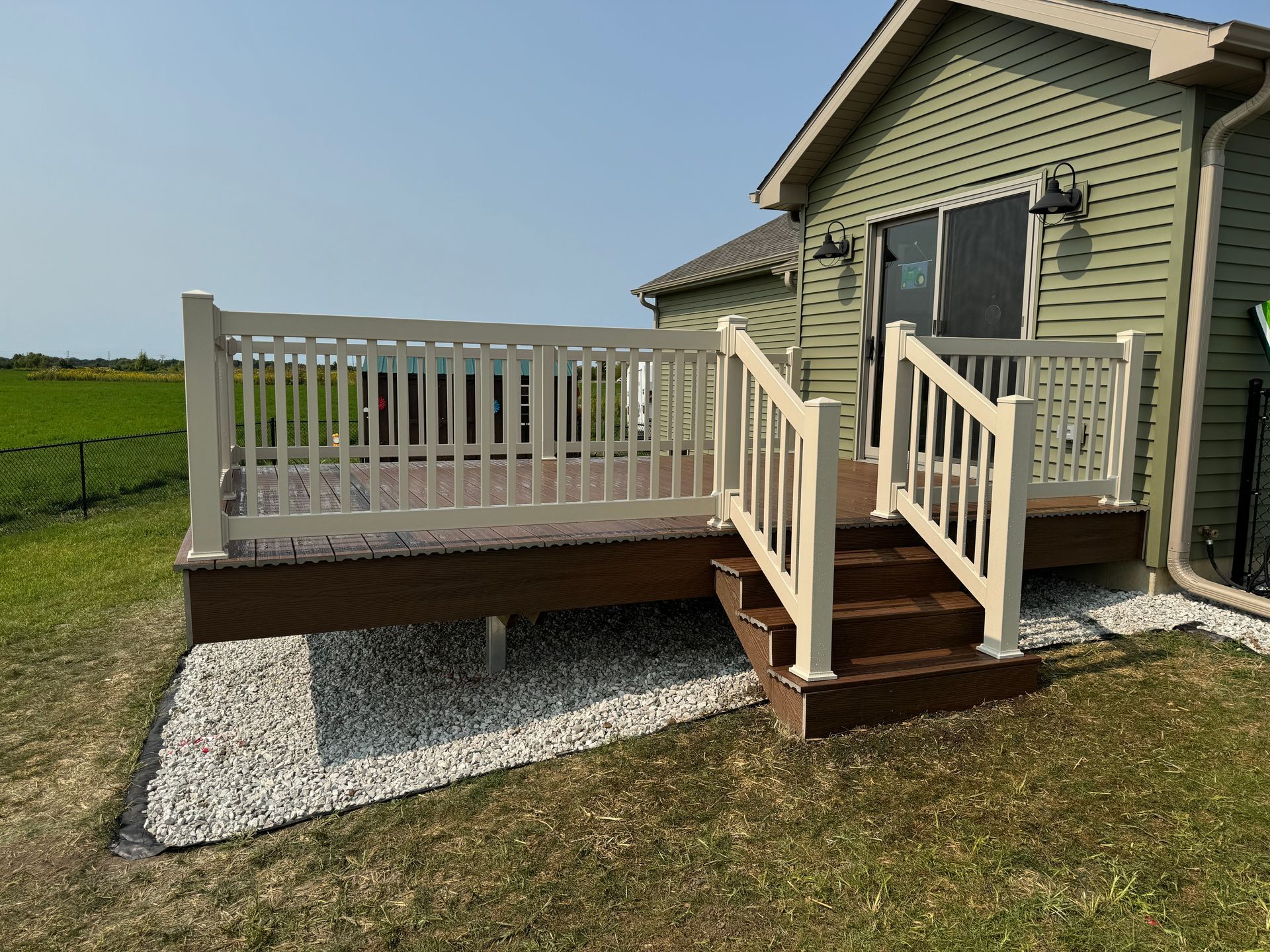 A nice deck with stairs leading up to it is in front of a house.
