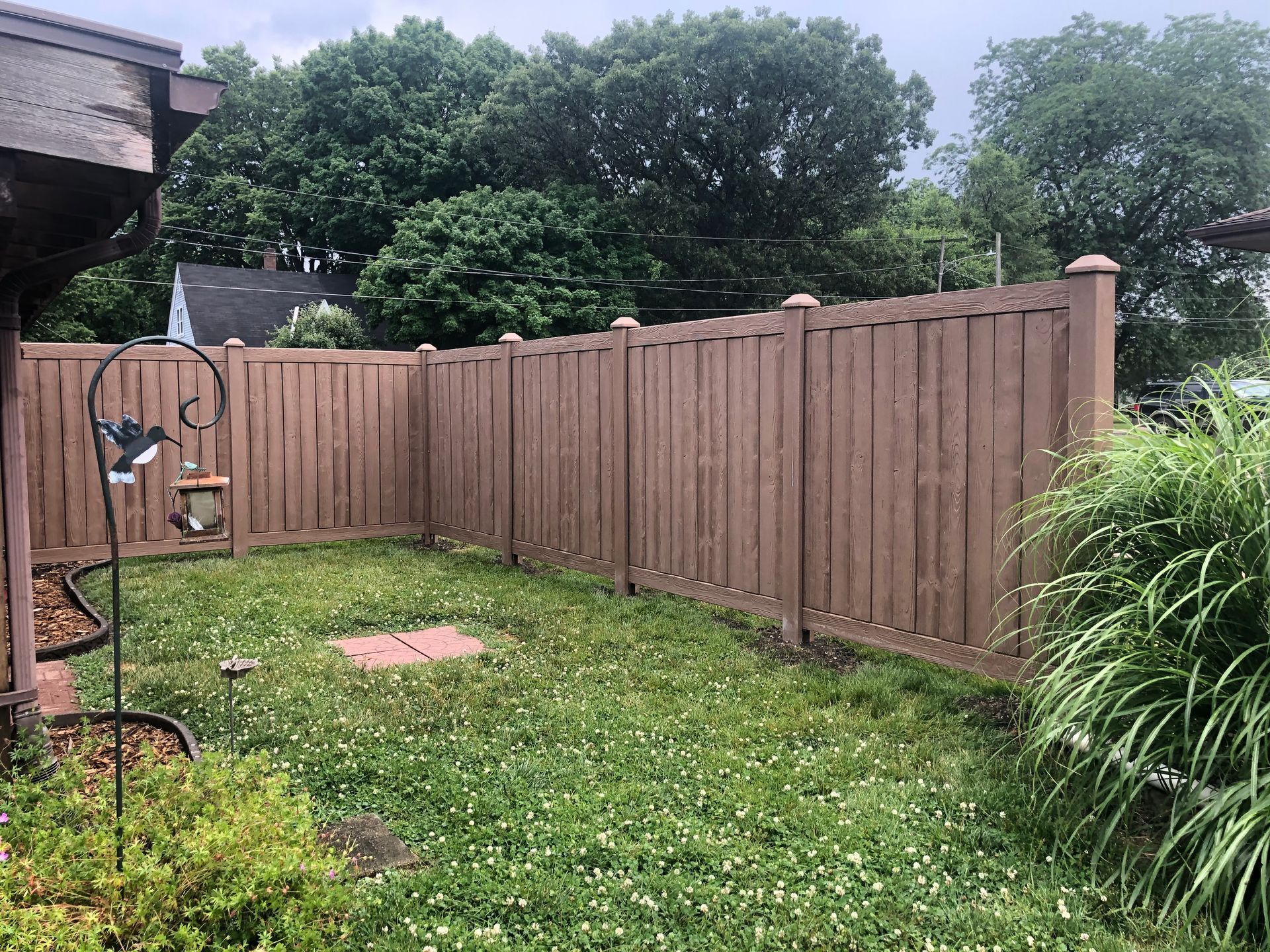 A wooden fence surrounds a lush green yard.