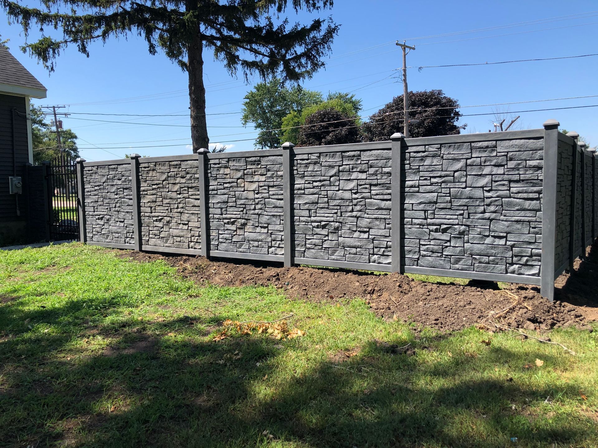A stone fence is sitting in the middle of a lush green field.
