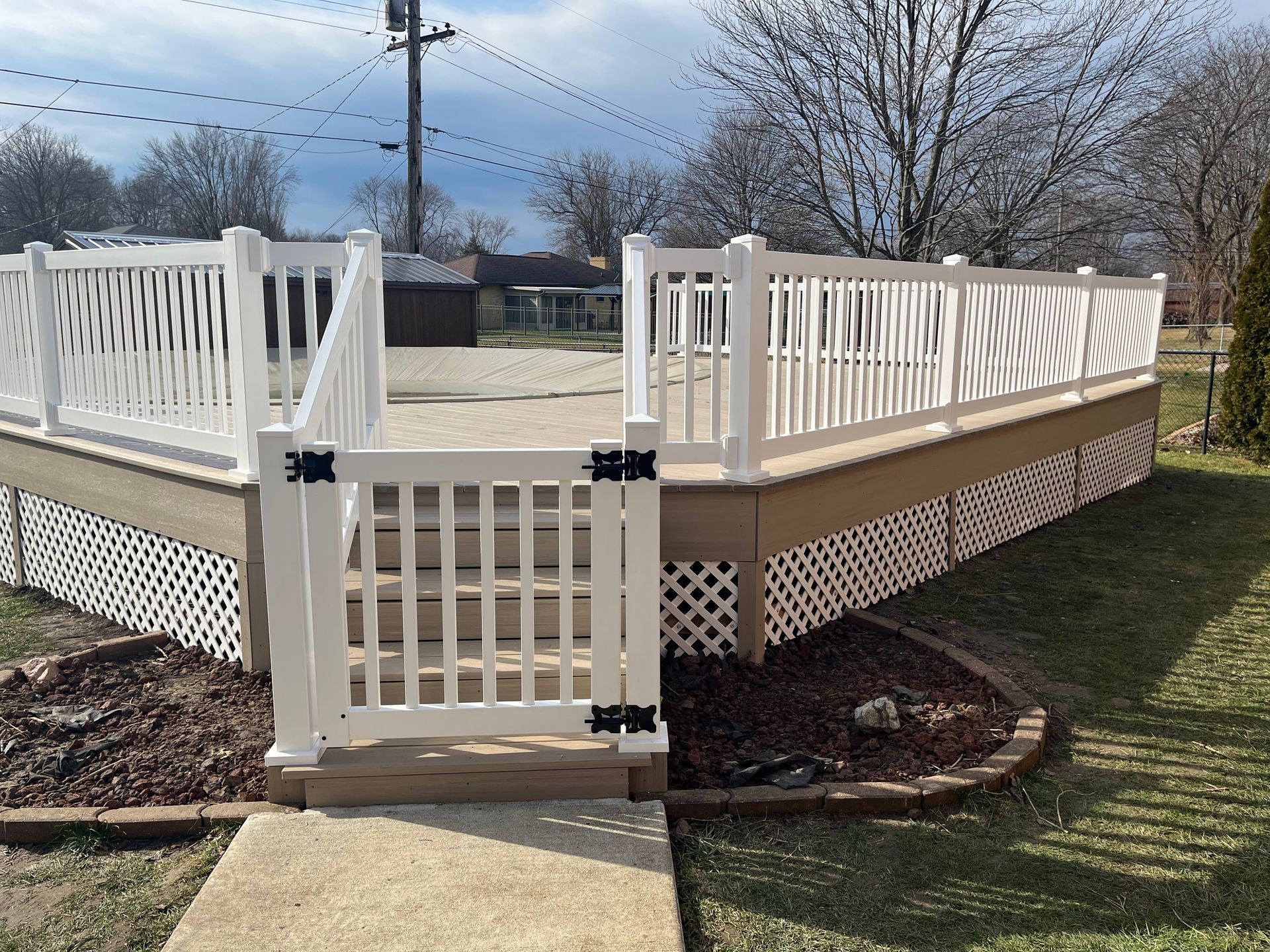 A white gate is leading to a deck with a fence around it.