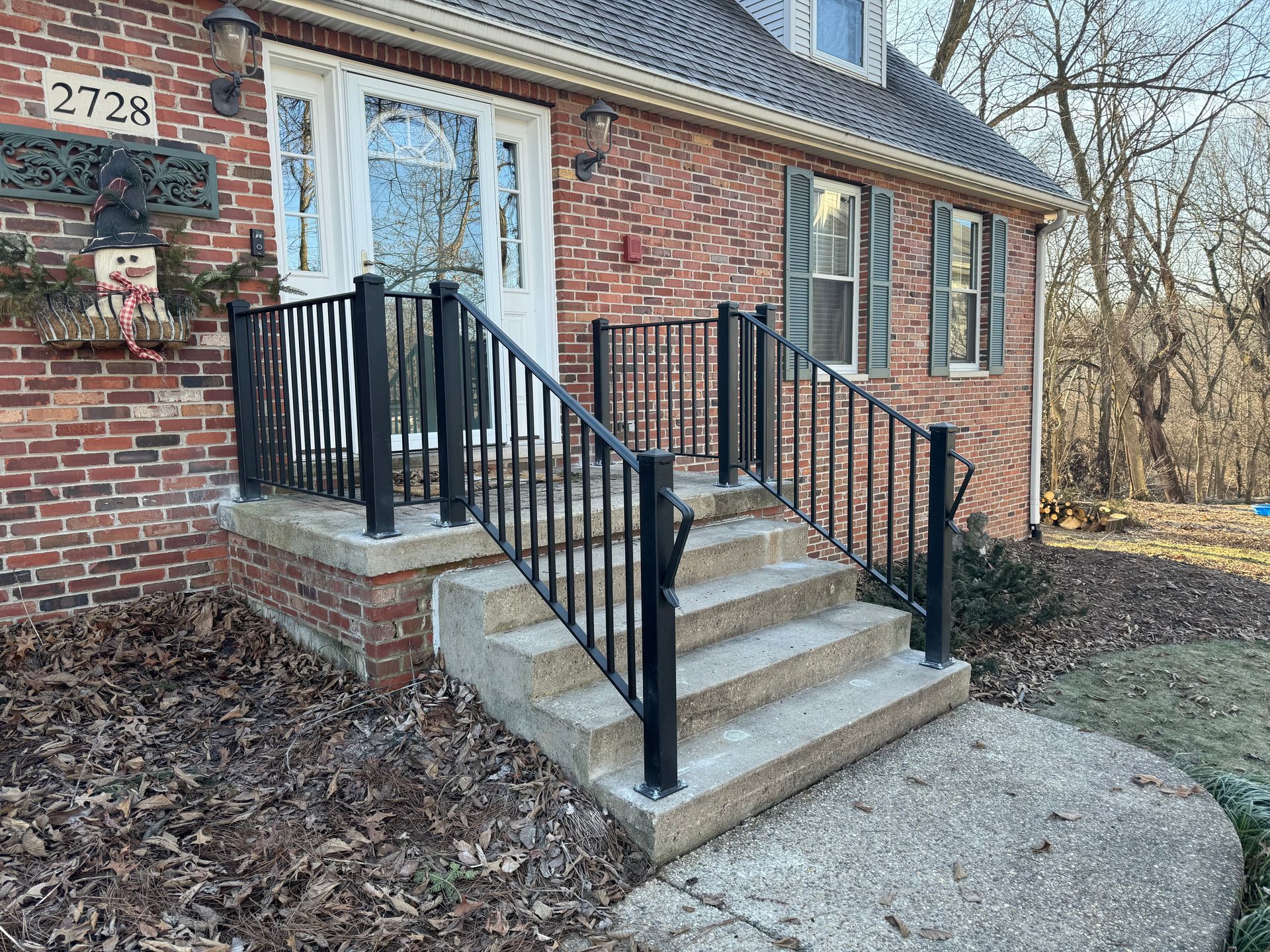 A brick house with a black railing and stairs.