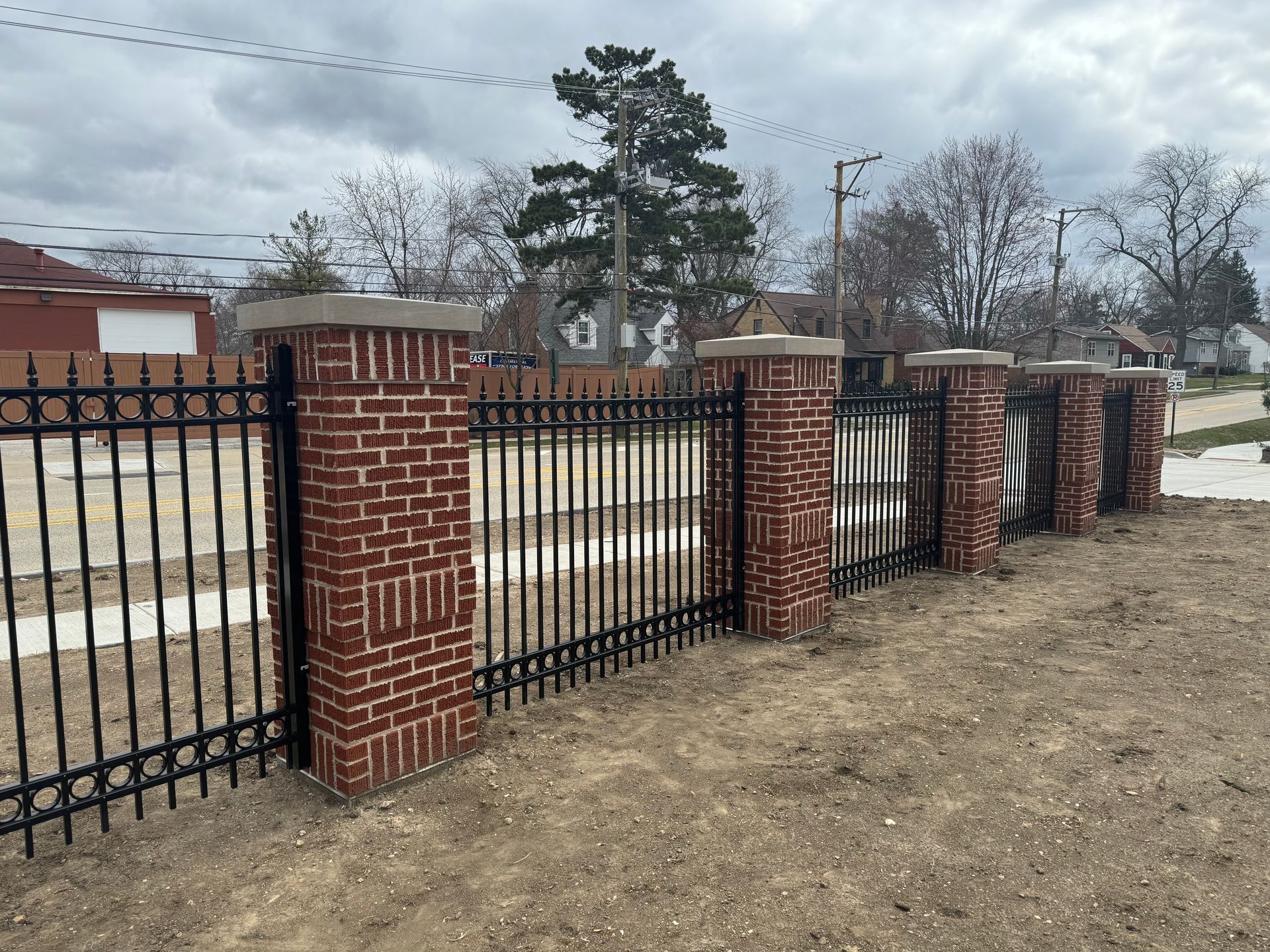 A metal fence with brick pillars surrounding it.
