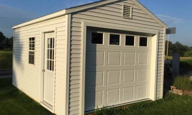 A white shed with a garage door and a window.