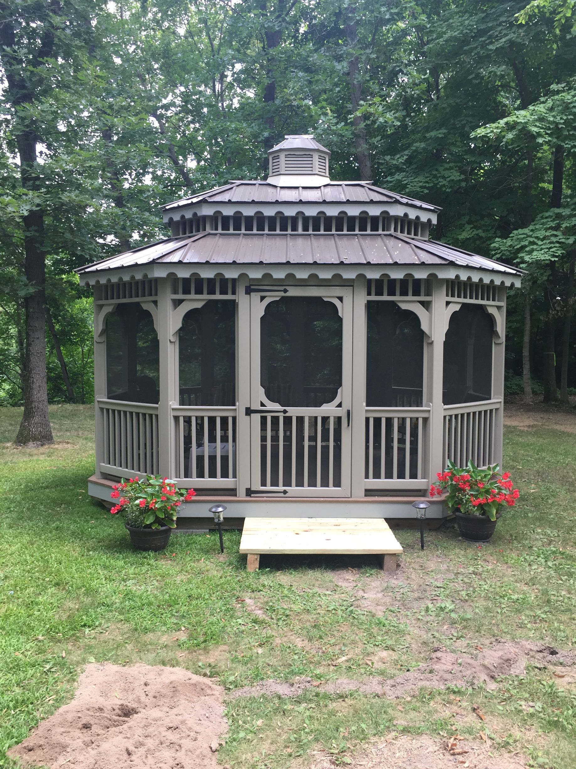 A gazebo is sitting in the middle of a lush green field.