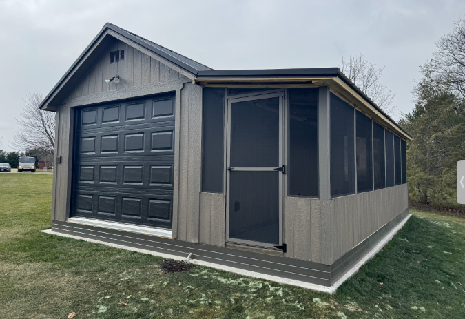 A shed with a screened in porch and a garage door.