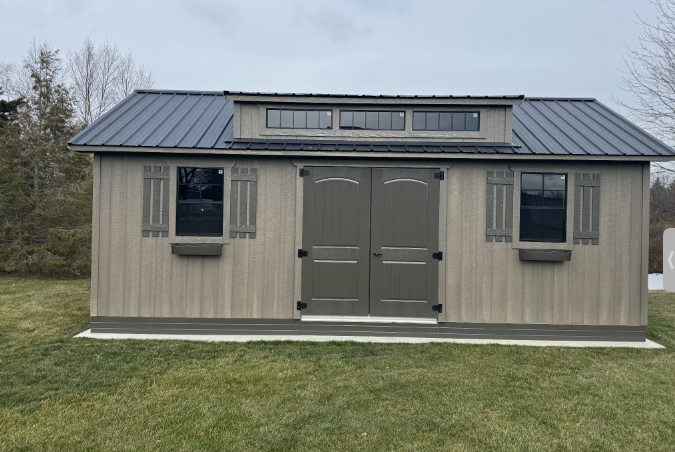 A shed with a metal roof is sitting on top of a lush green field.