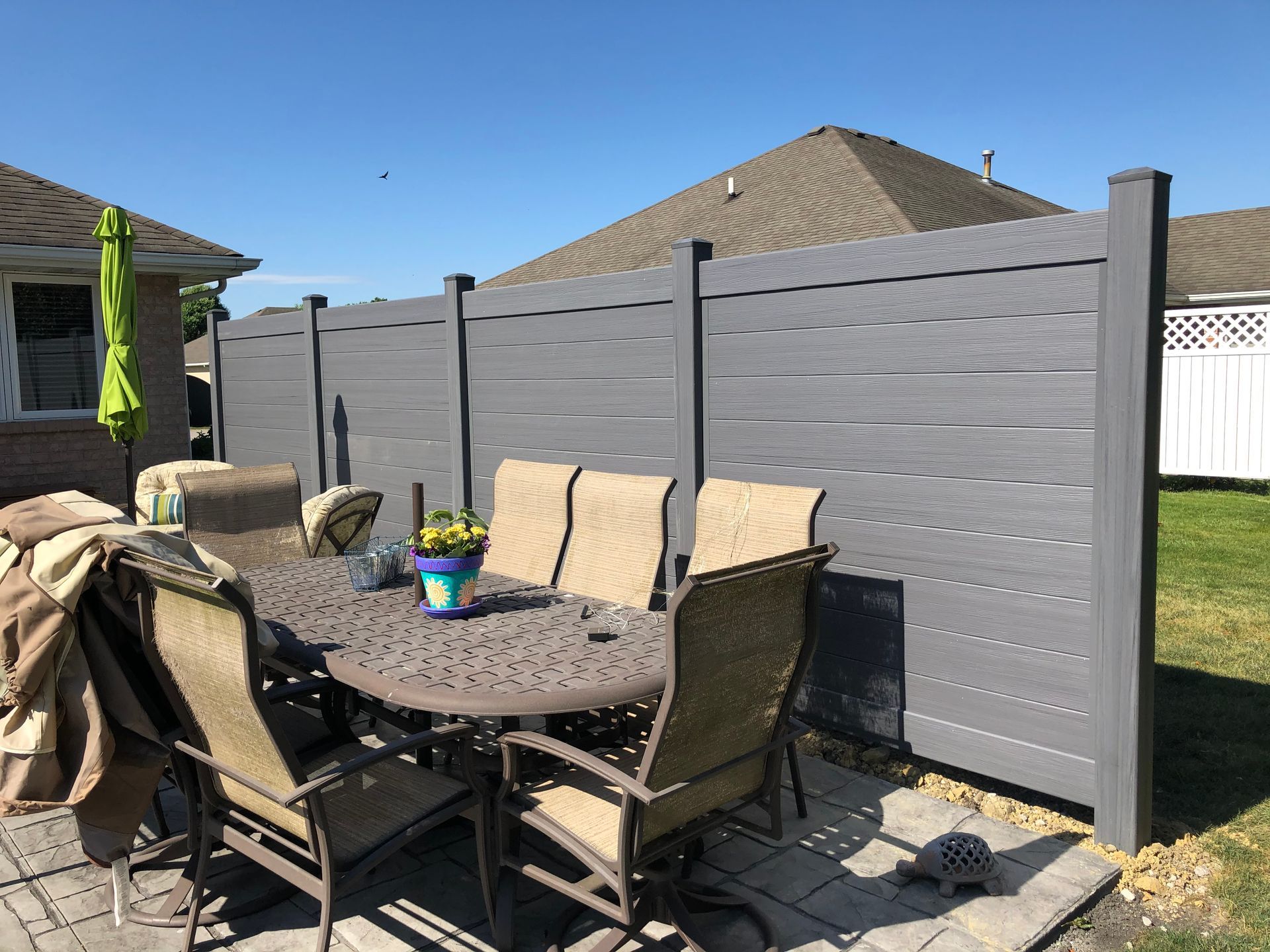 A patio with a table and chairs in front of a fence.