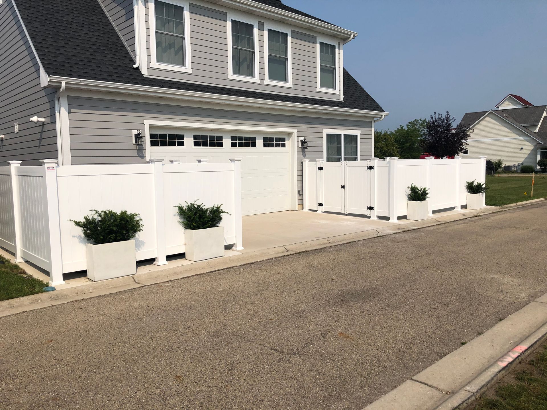A house with a white fence and planters in front of it.