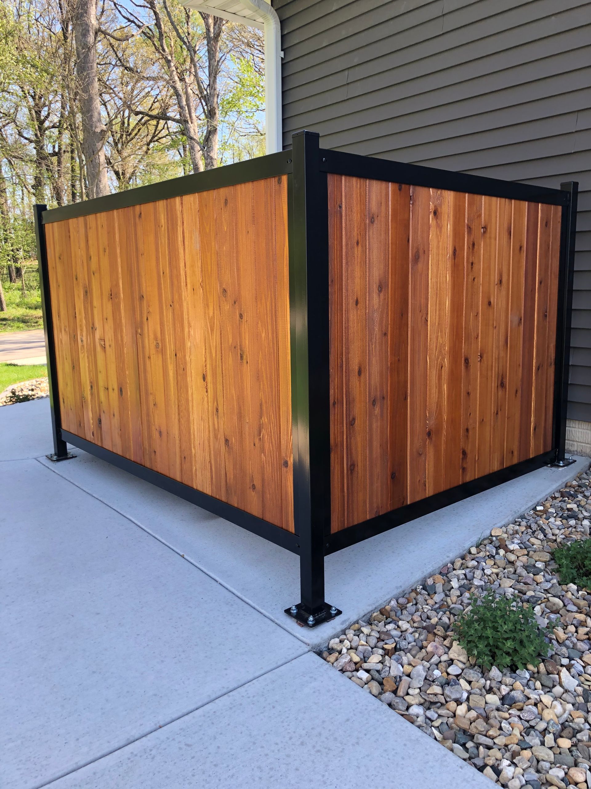 A wooden fence is sitting on a sidewalk next to a house.