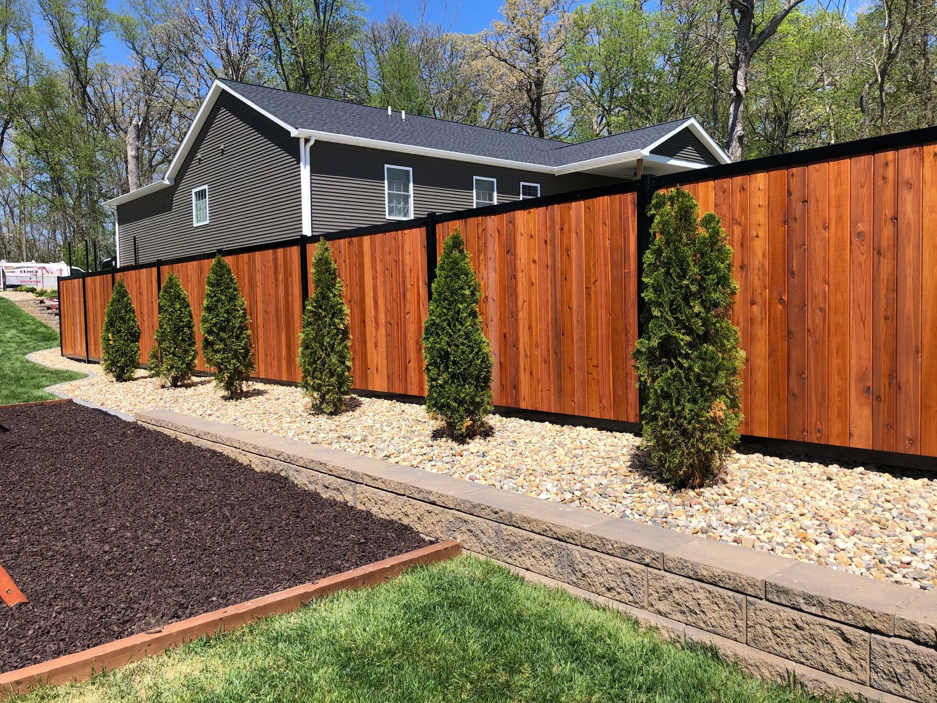 A wooden fence with trees in front of a house.