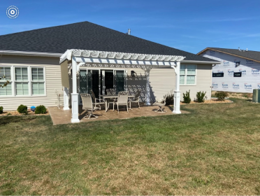 There is a pergola in the backyard of a house.